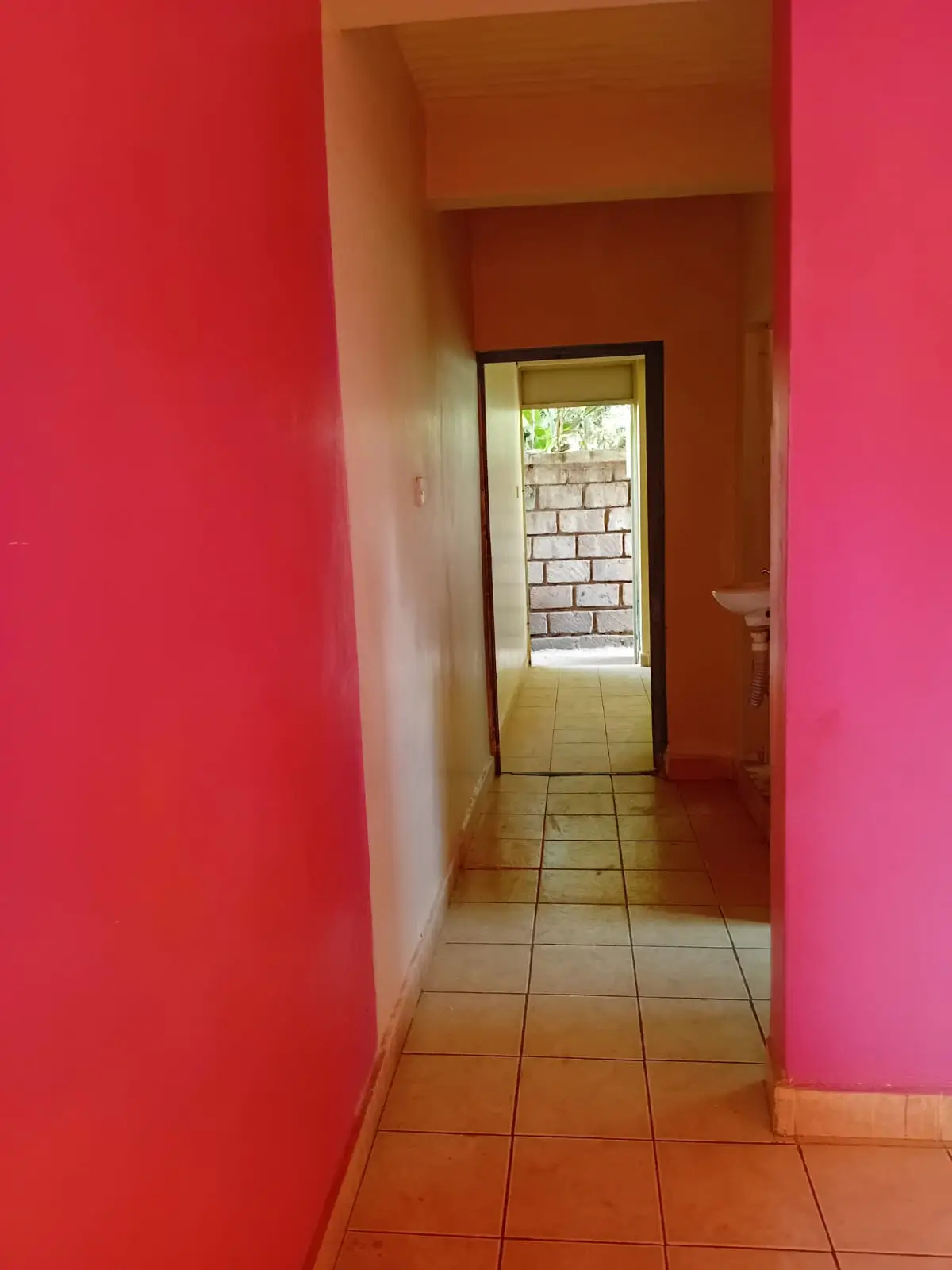 Bright corridor with vibrant pink walls and terracotta tiles