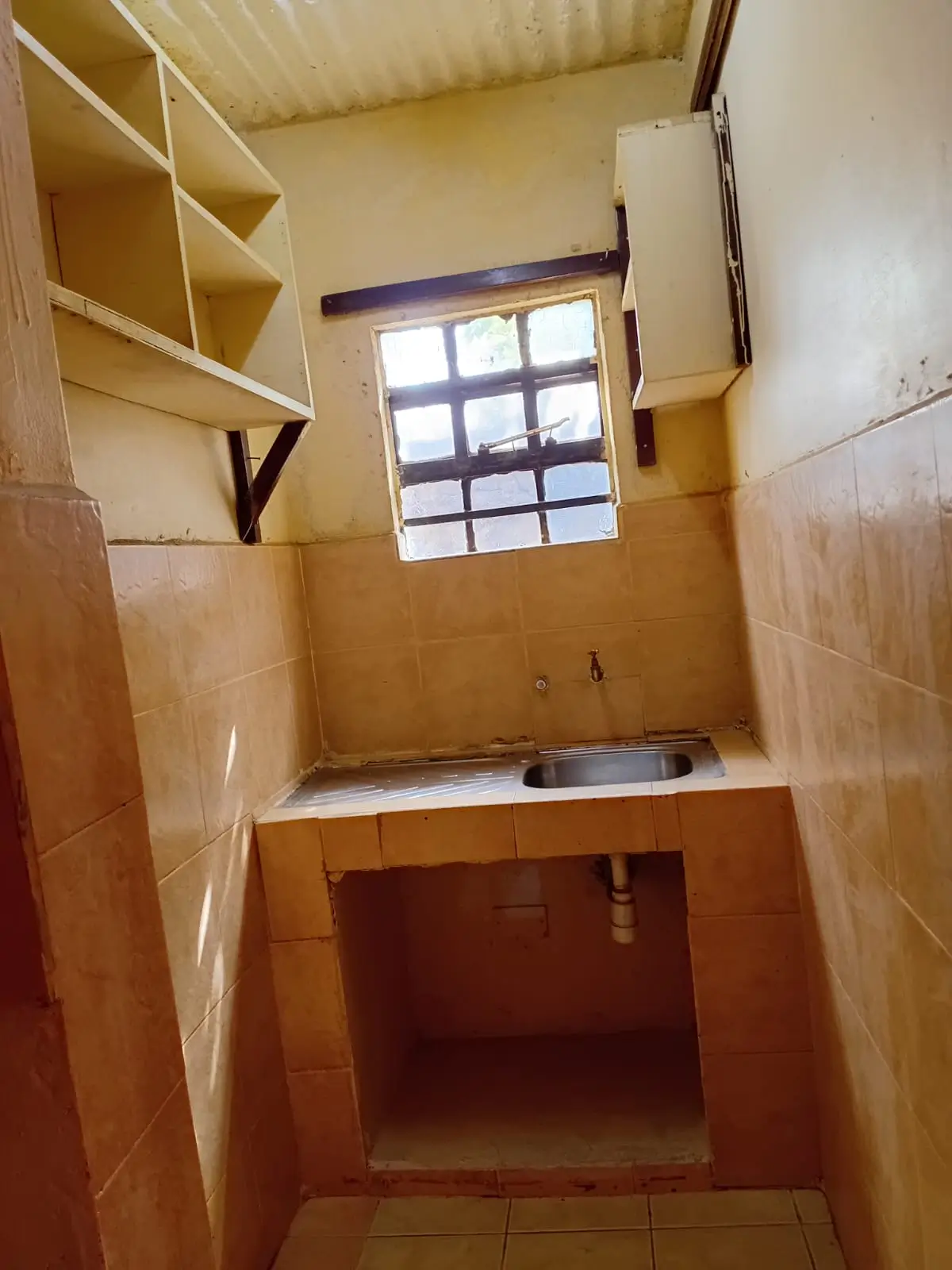 Compact kitchen with tiled walls and window lighting