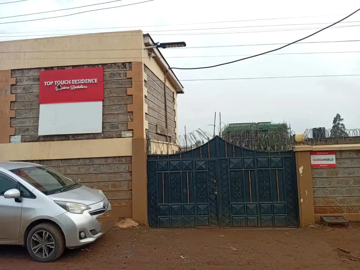 Residential compound entrance with steel gates and signage
