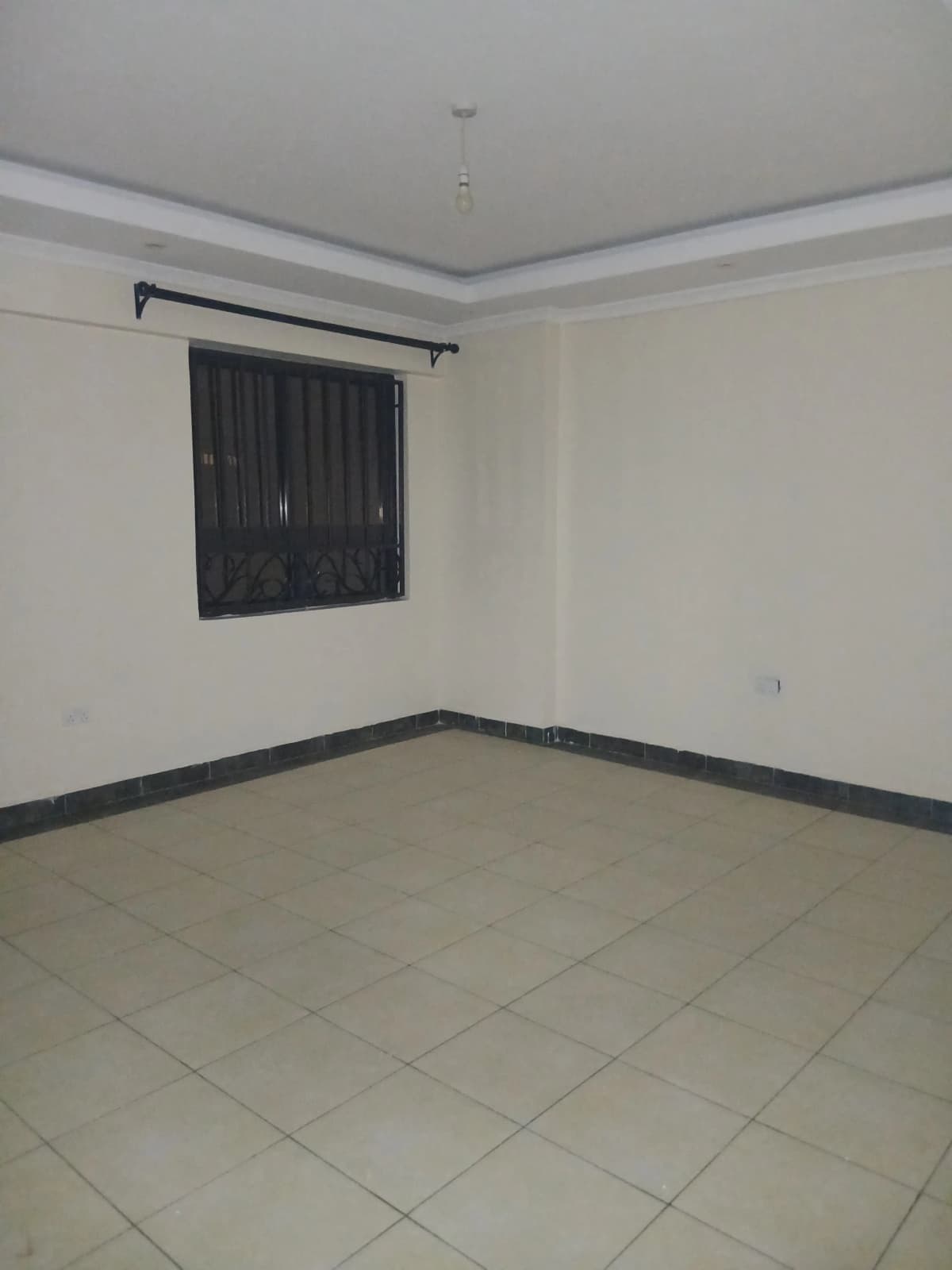 Empty bedroom with tiled floor and barred window