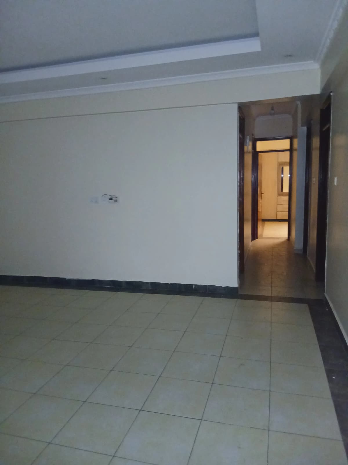 Empty living room with tiled floor and corridor access