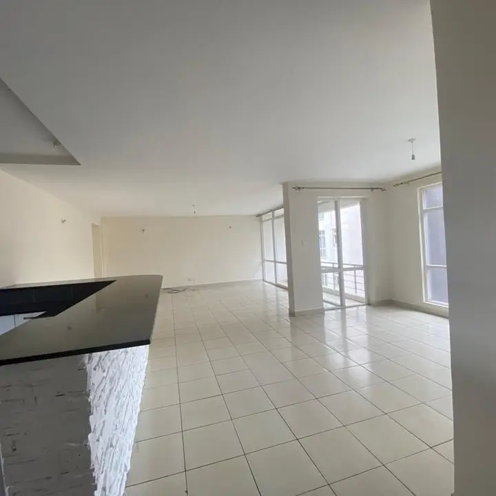 Open-plan living and kitchen with tile flooring, bright windows