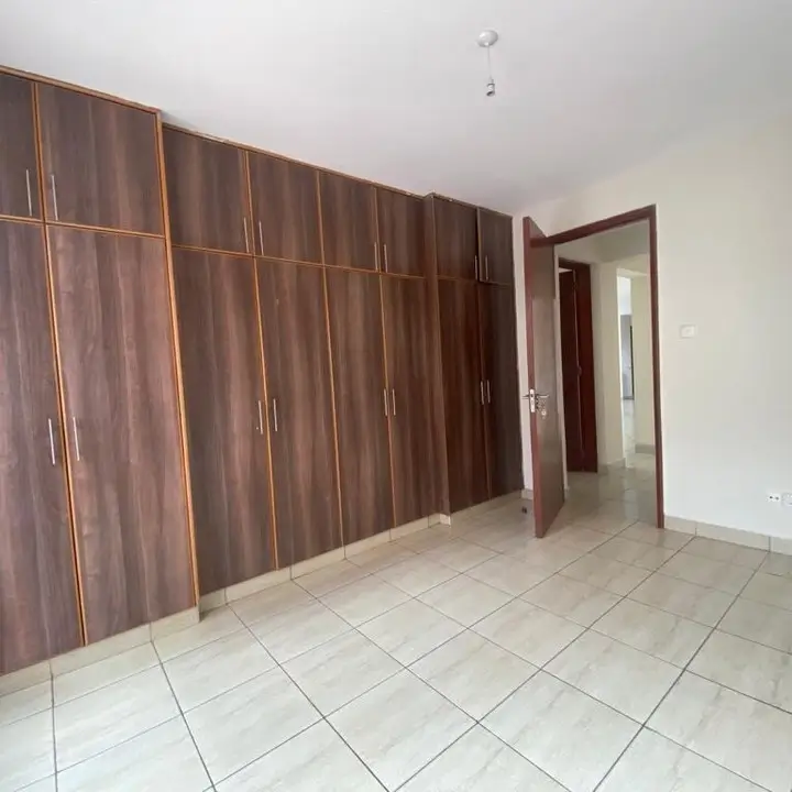 Spacious bedroom with built-in wooden wardrobes, tiled floors