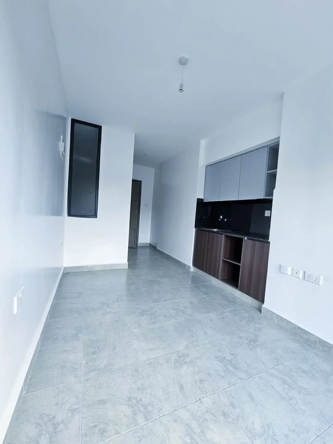 Modern open-plan kitchen with black cabinetry and grey tile flooring