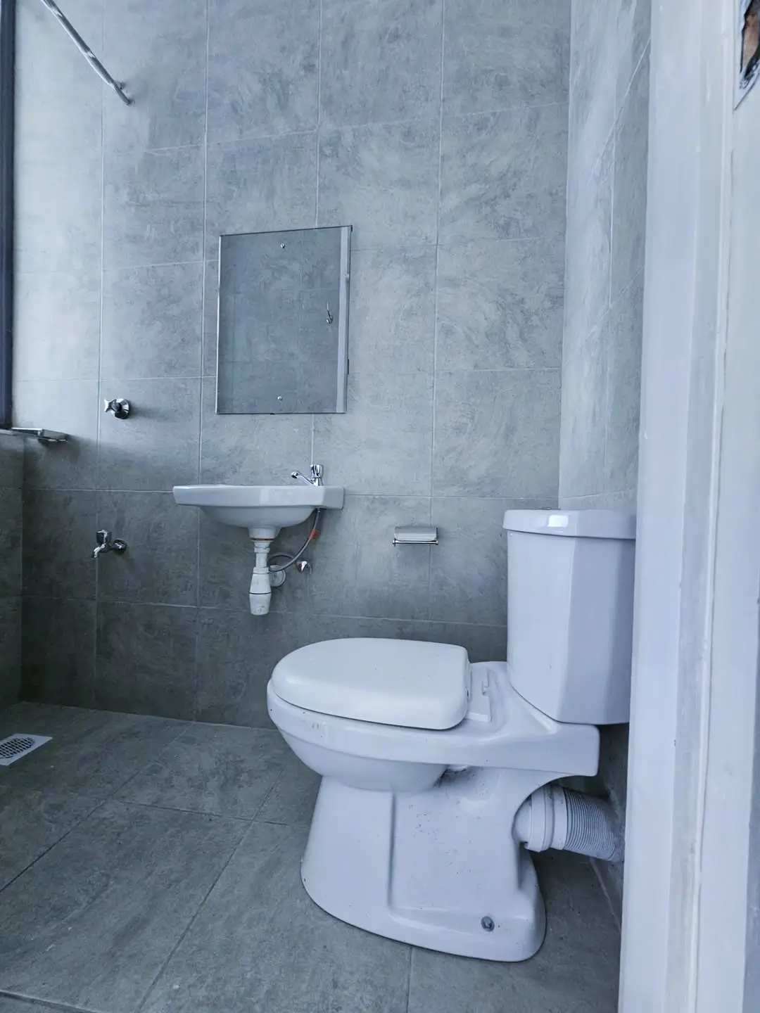 Modern bathroom with toilet, sink, mirror, gray tile walls