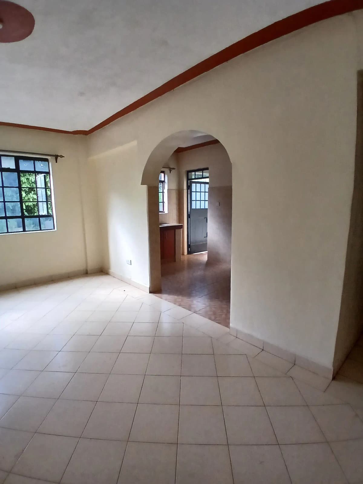 Spacious empty living area with tiled floors and arched doorway