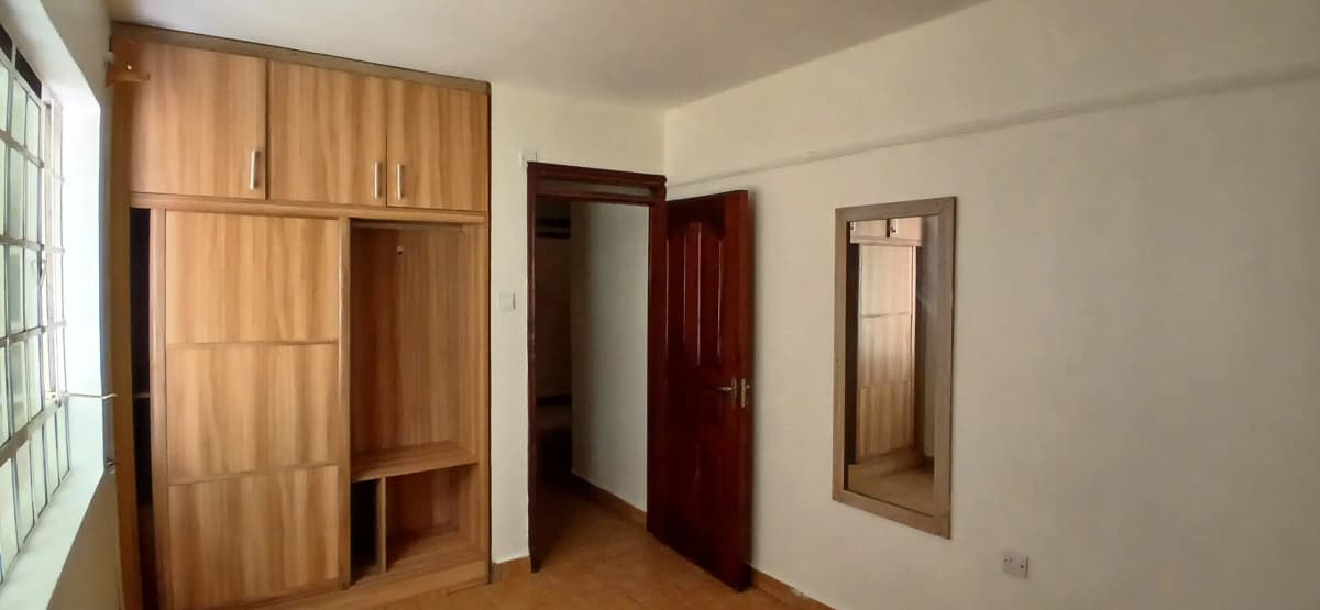 Unfurnished bedroom with wooden wardrobe and multiple doors