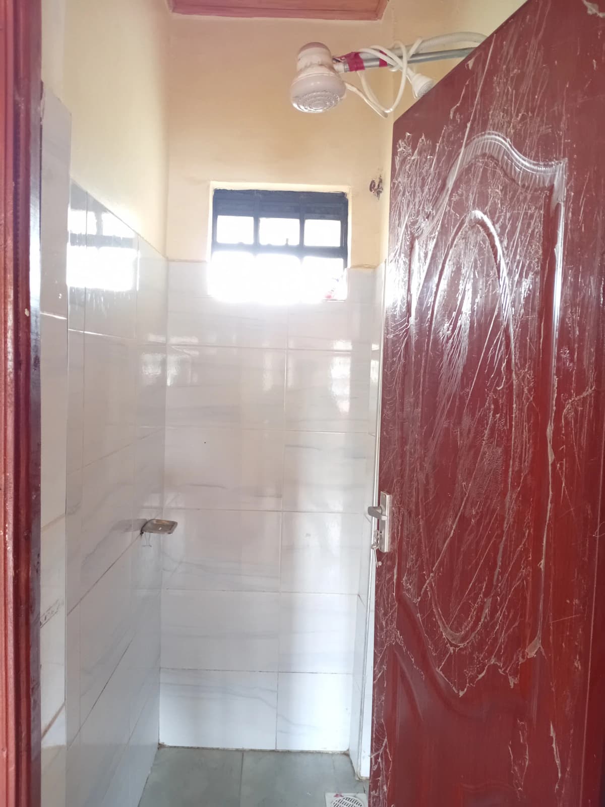 Compact bathroom with tiled shower enclosure and red door