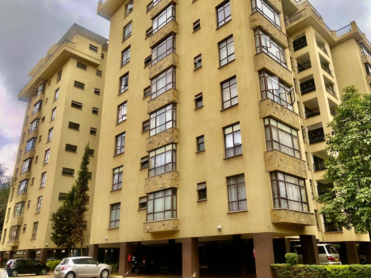 Yellow apartment building facade with ground-level parking bays