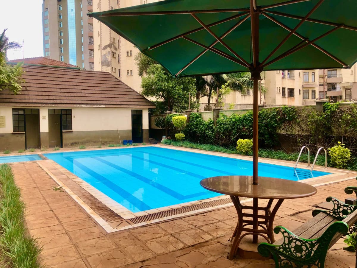 Resort-style swimming pool with green umbrella and lounging area