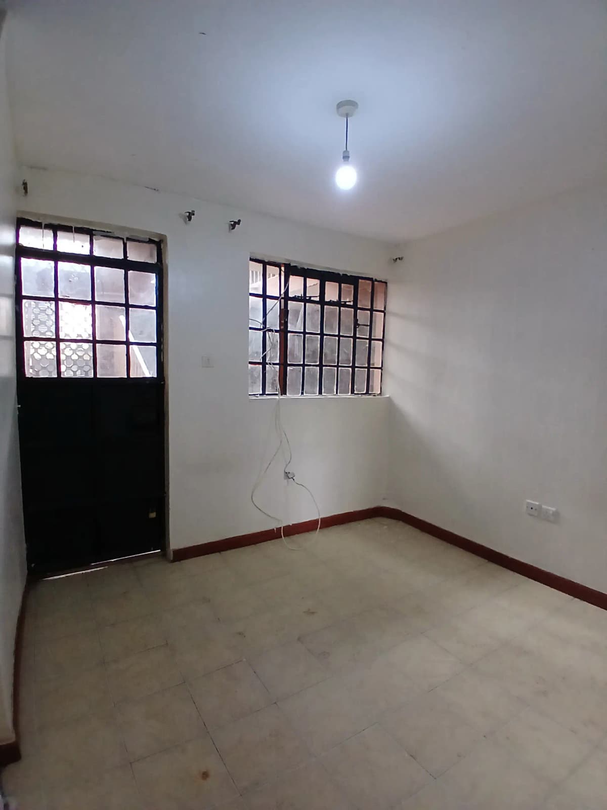 Unfurnished bedroom with barred window and concrete floor