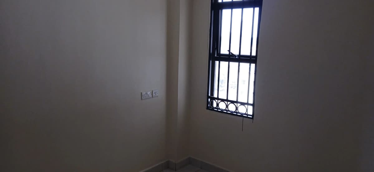 Empty bedroom with barred window and plain walls