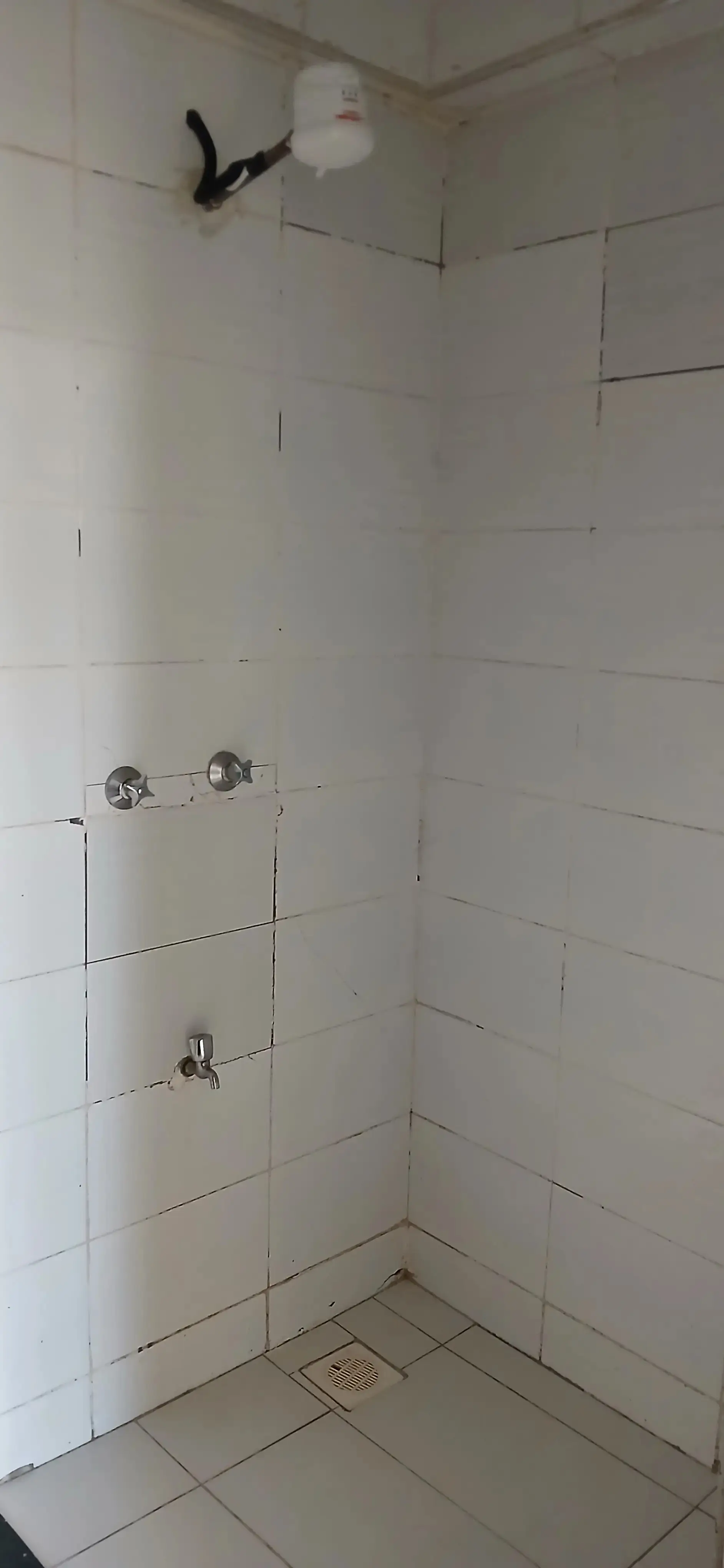 Tiled shower enclosure under construction with plumbing fixtures