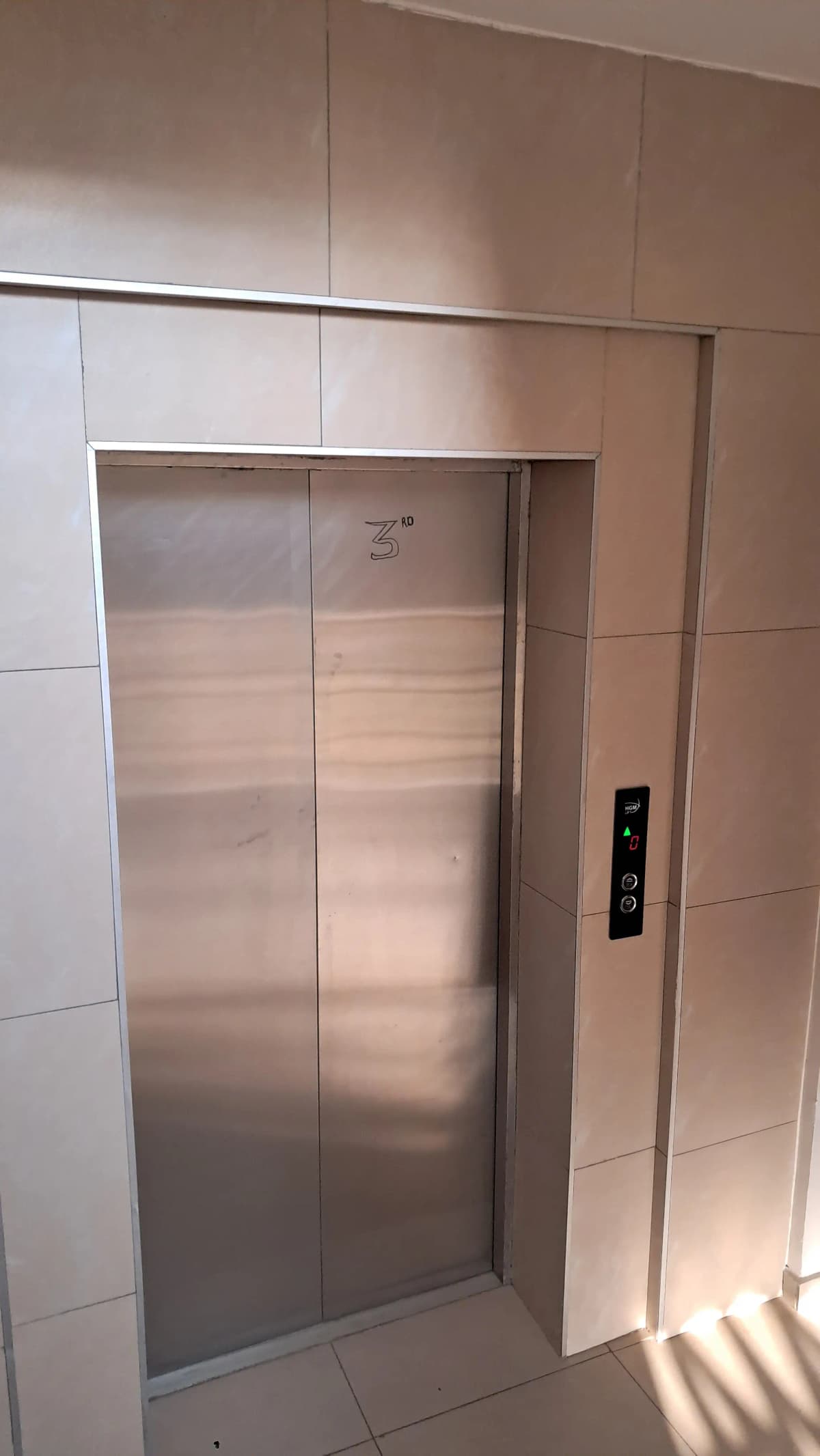Modern stainless steel elevator in tiled lobby area