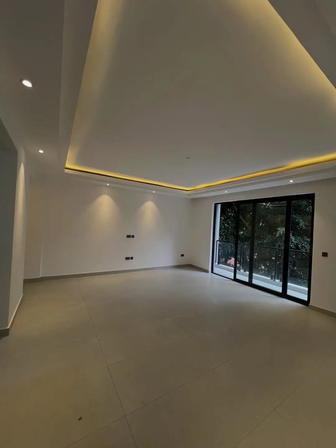 Empty modern living room with coved ceiling and glass doors