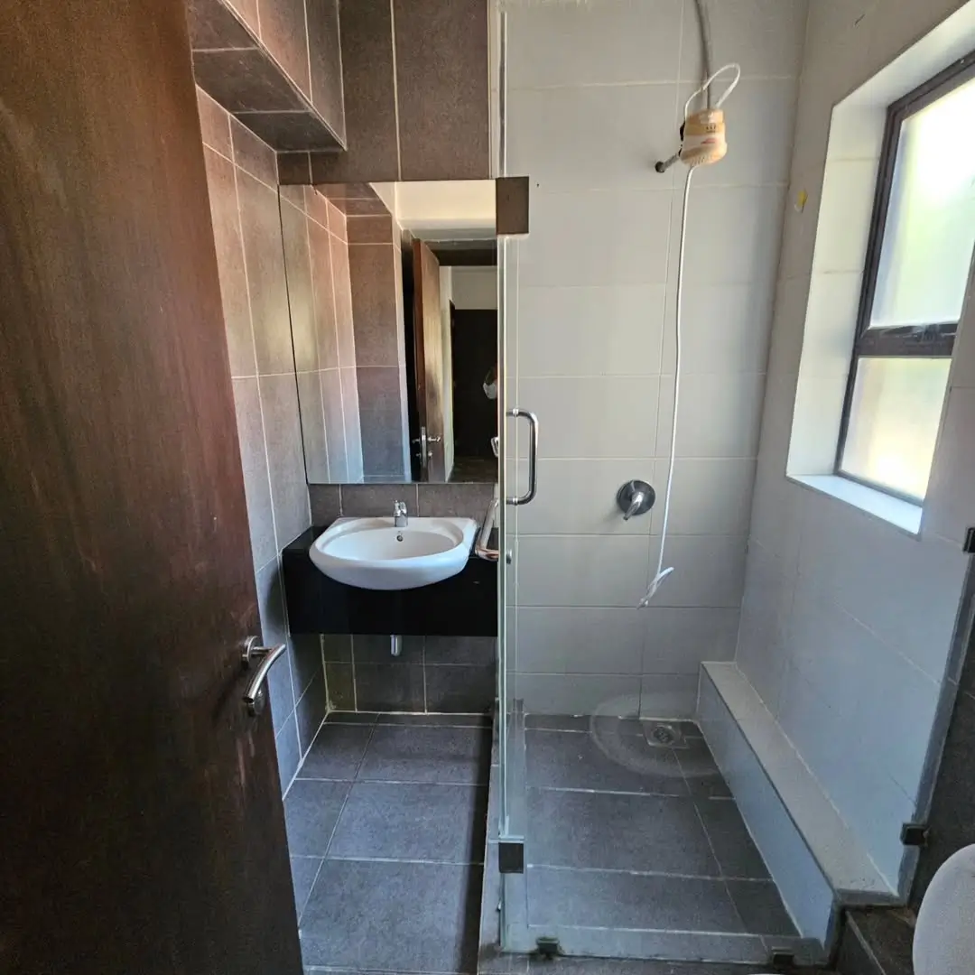 Modern bathroom with round sink, dark tiles, shower enclosure