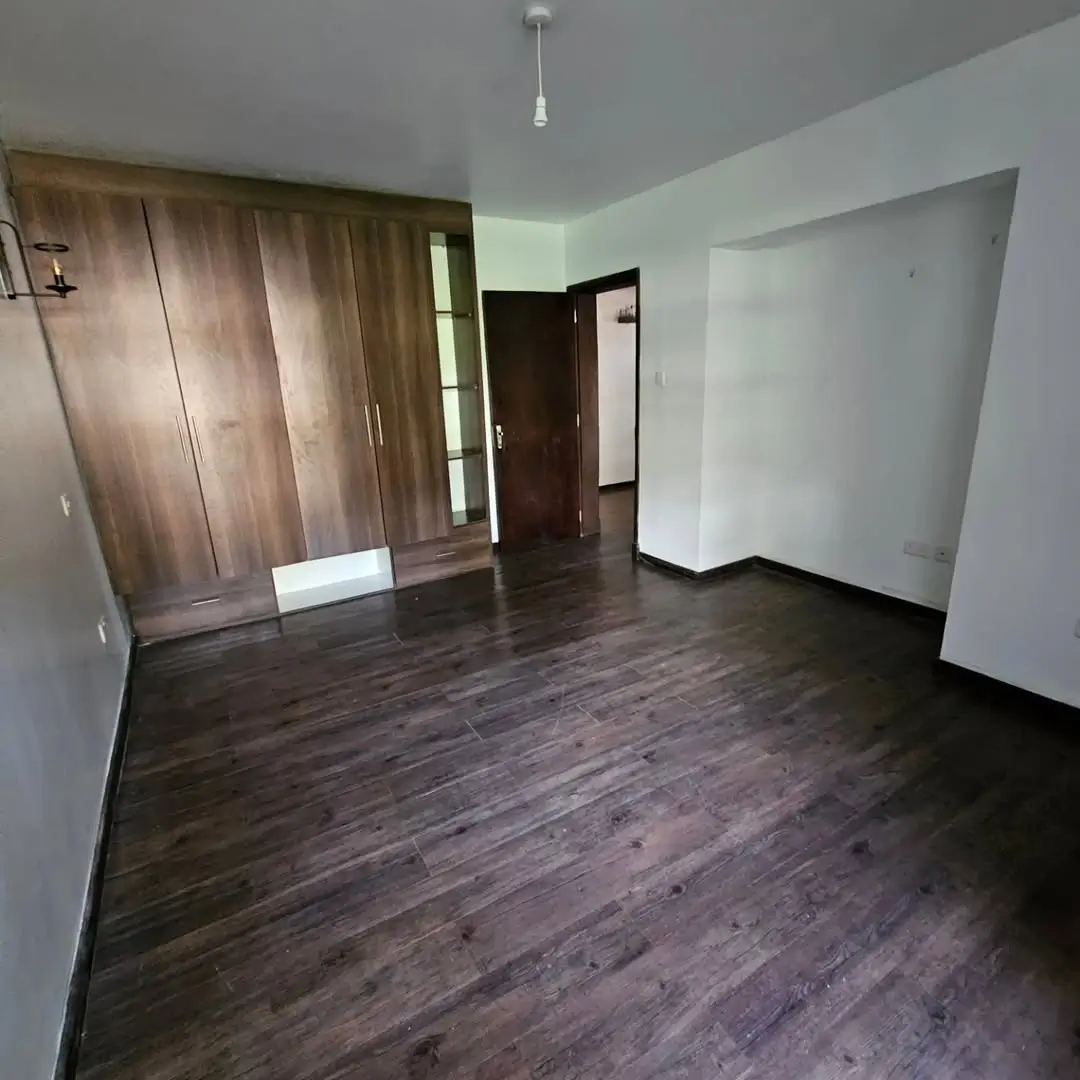Spacious bedroom with wooden flooring and built-in wardrobes