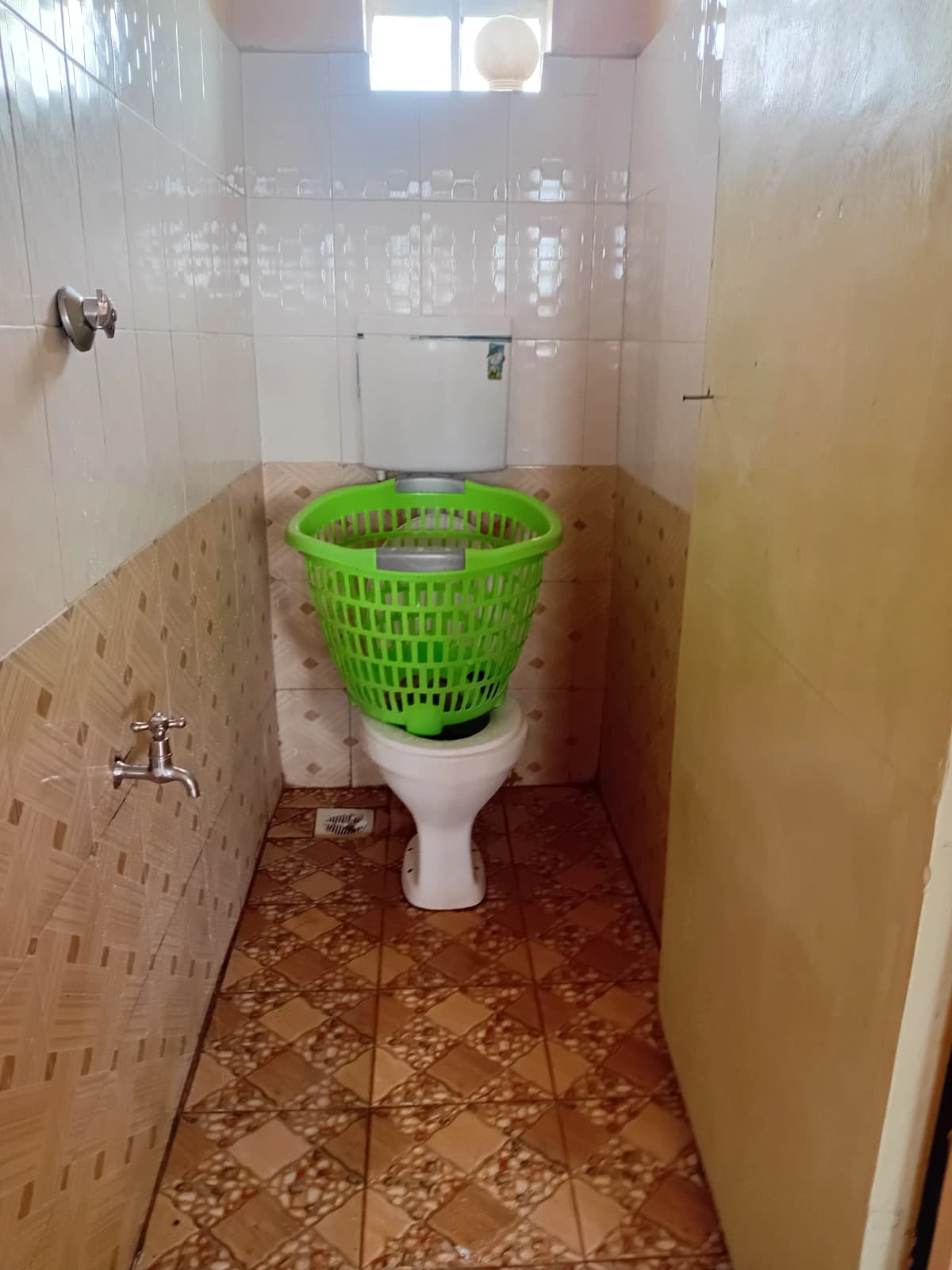 Small bathroom with toilet and laundry basket storage