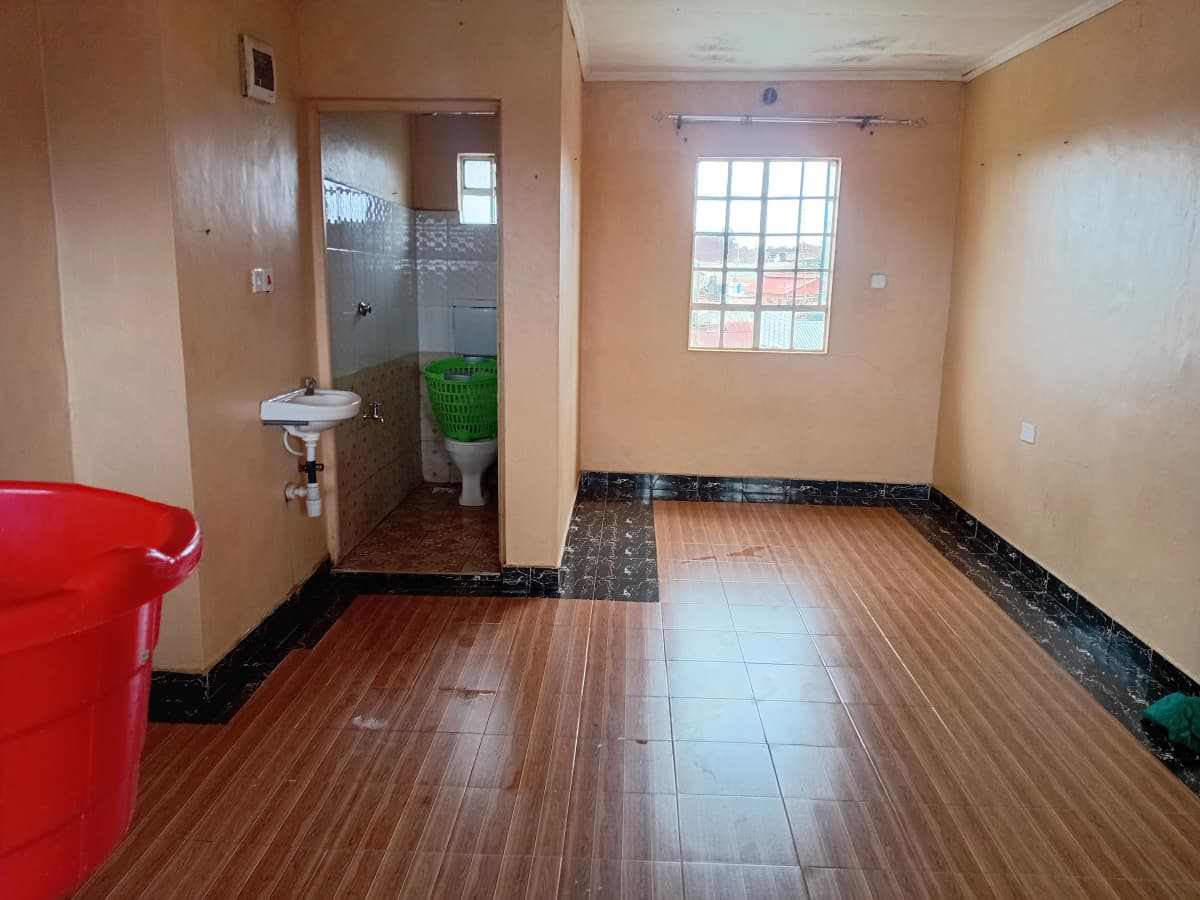 Open living space with wooden flooring and bathroom entrance visible