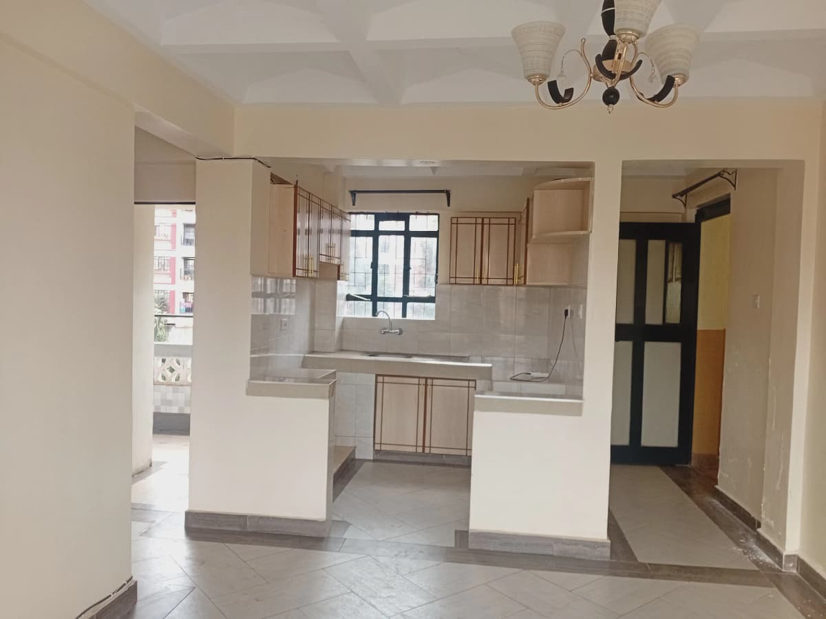 Open-plan kitchen with cream cabinetry and living area beyond