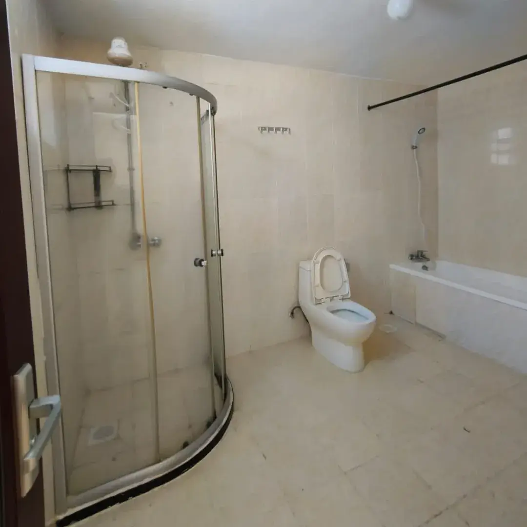 Modern bathroom with curved glass shower, toilet, and bathtub
