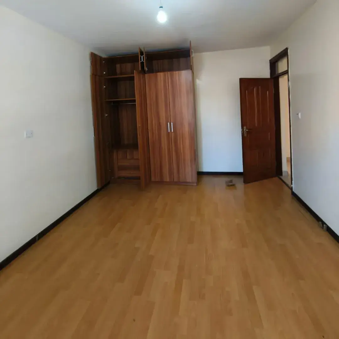 Spacious bedroom with wooden wardrobe and laminate flooring