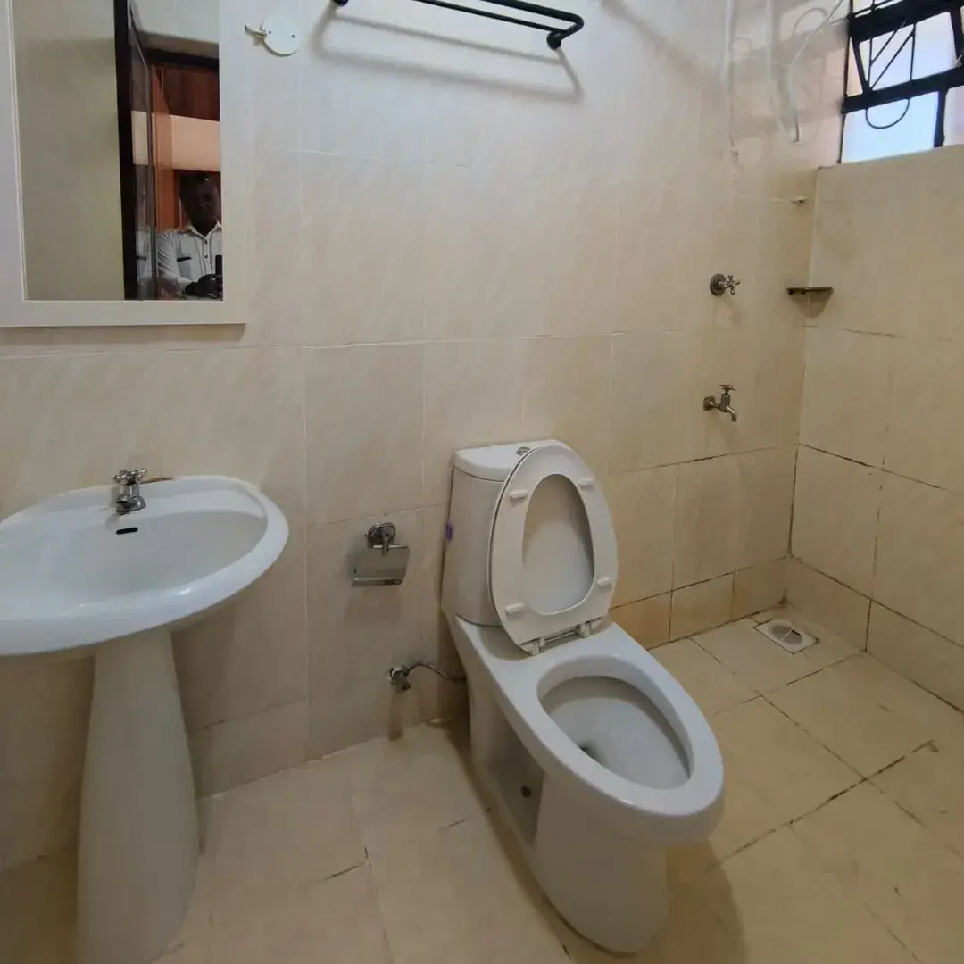 Simple bathroom with pedestal sink, toilet, and tiled walls