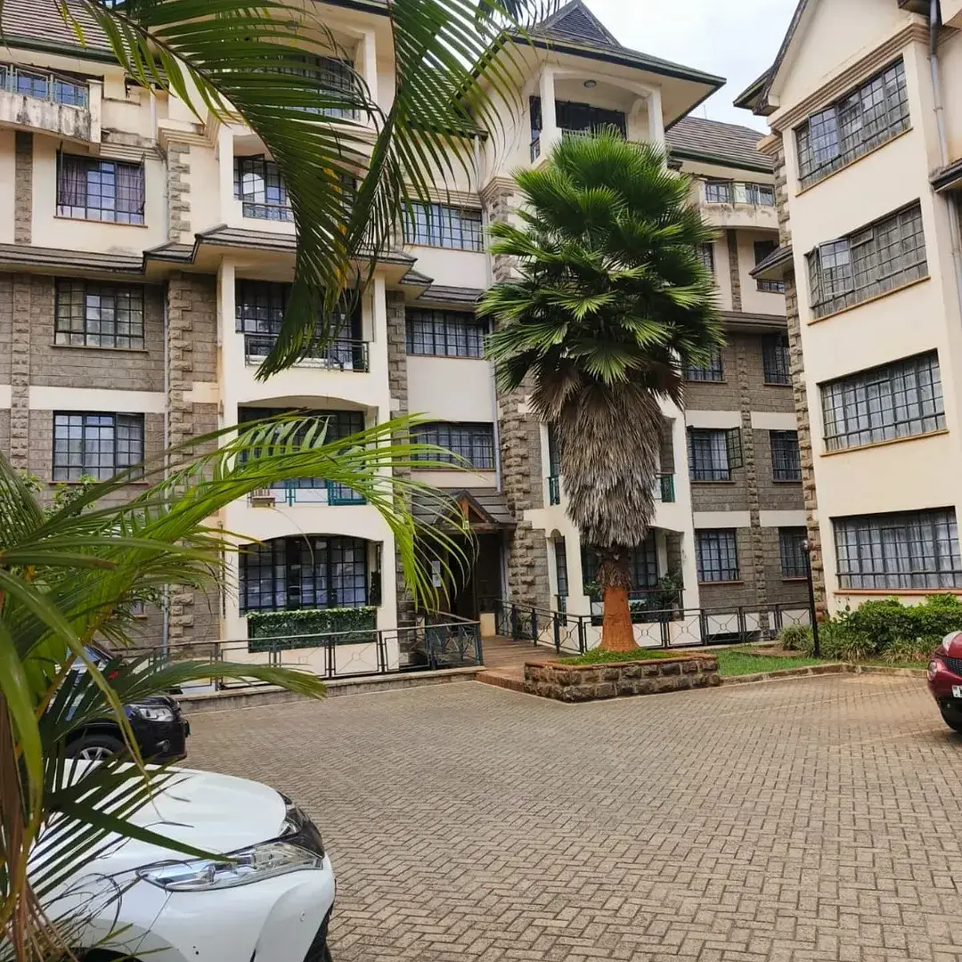 Multi-story residential building with manicured compound and parking