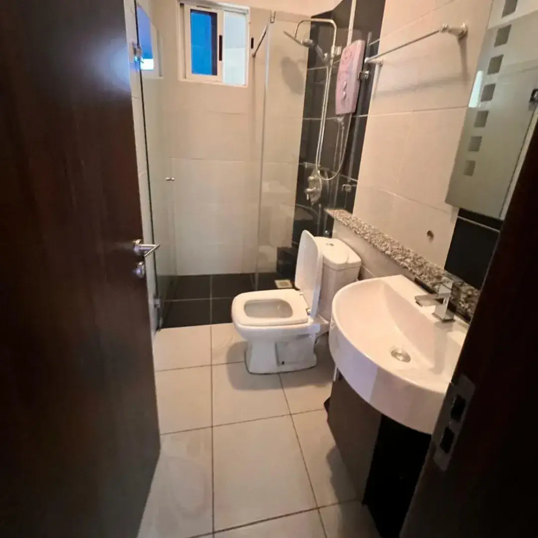 Compact bathroom with toilet, sink, and shower enclosure