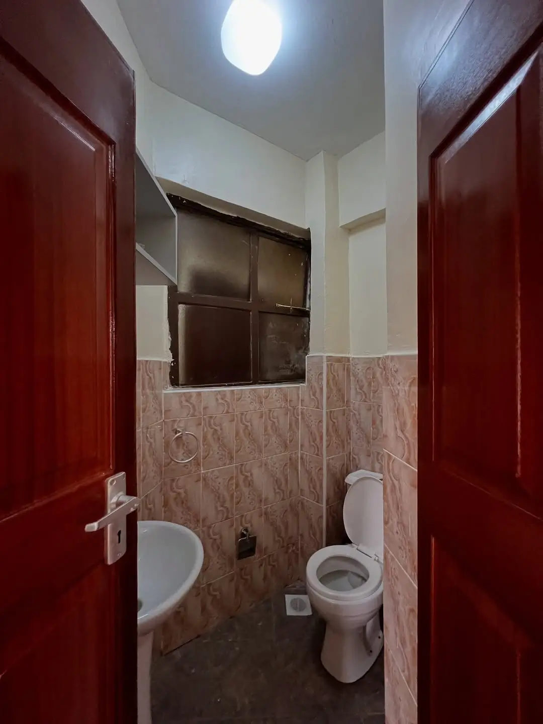 Compact bathroom with toilet, sink, and tiled walls