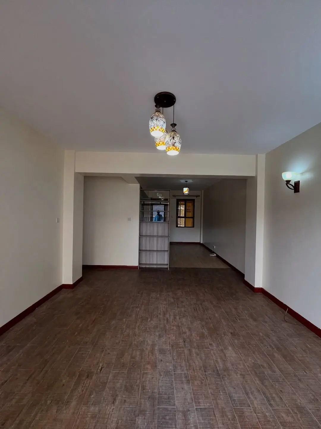 Empty living room with dark wood flooring and pendant lighting
