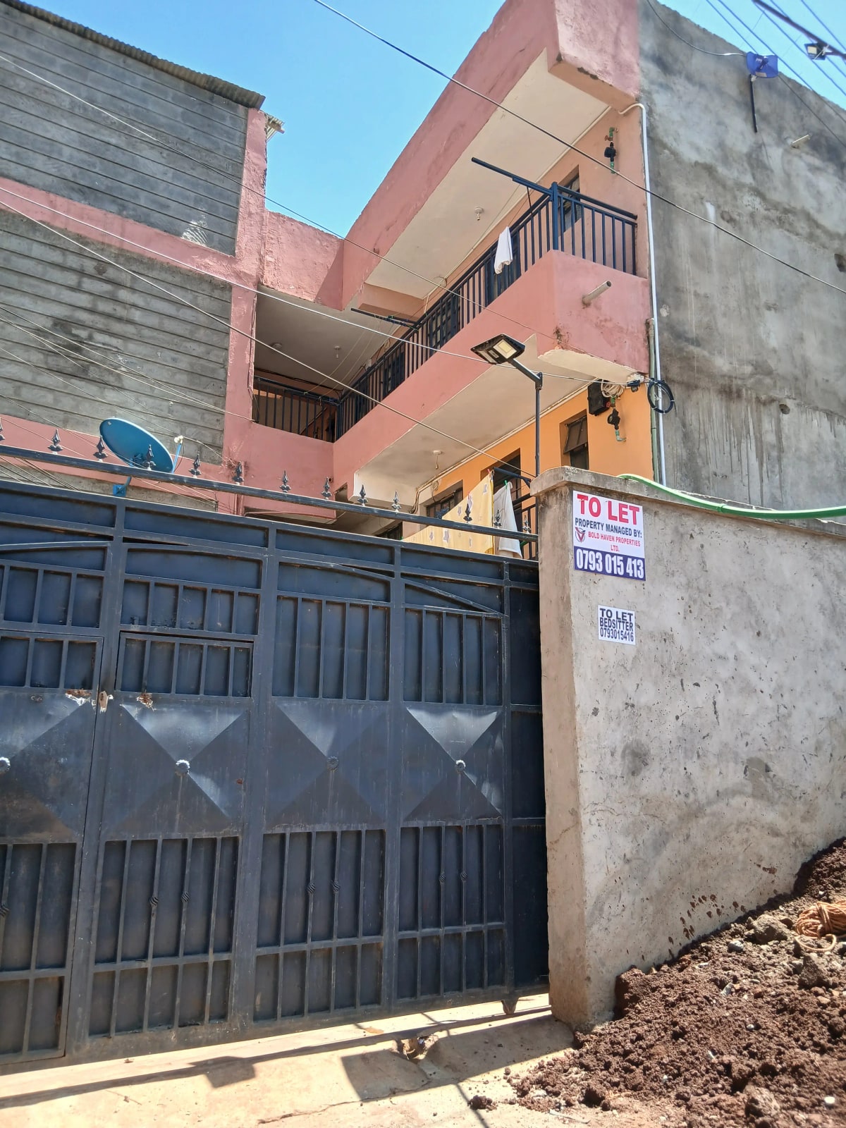 Multi-story residential building with metal gate and compound entrance
