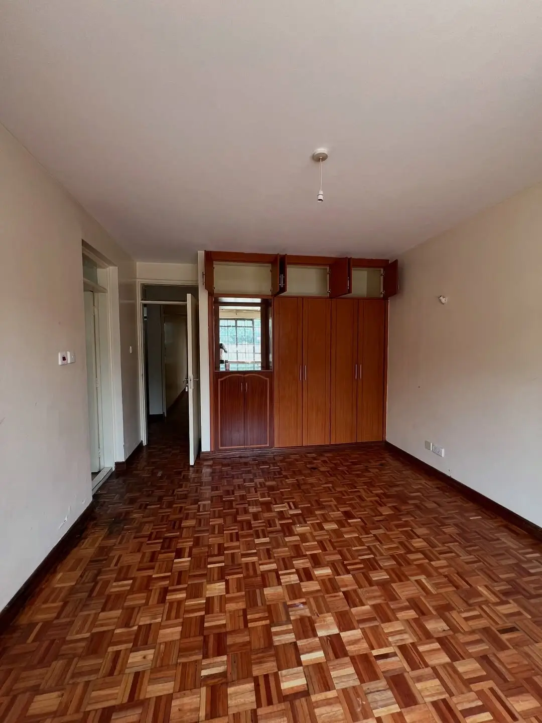 Spacious bedroom with parquet flooring and built-in wardrobes