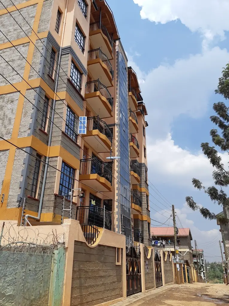 Multi-story residential building facade with balconies and ground-level parking
