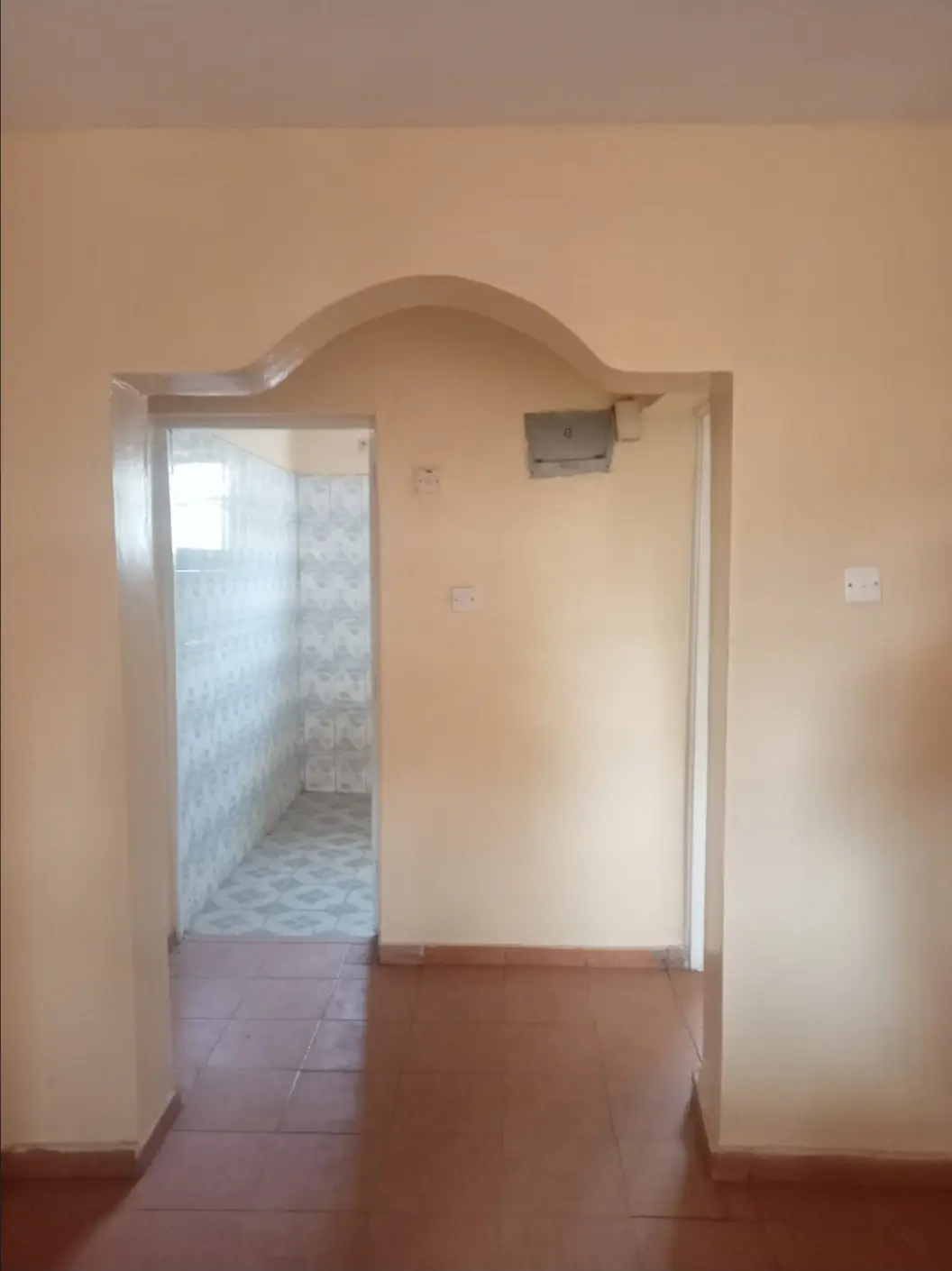 Corridor with arched doorway and tiled bathroom entrance