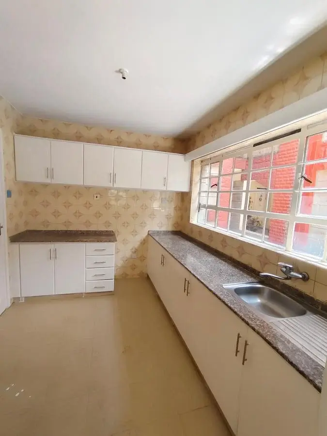Spacious galley kitchen with white cabinetry and granite counters