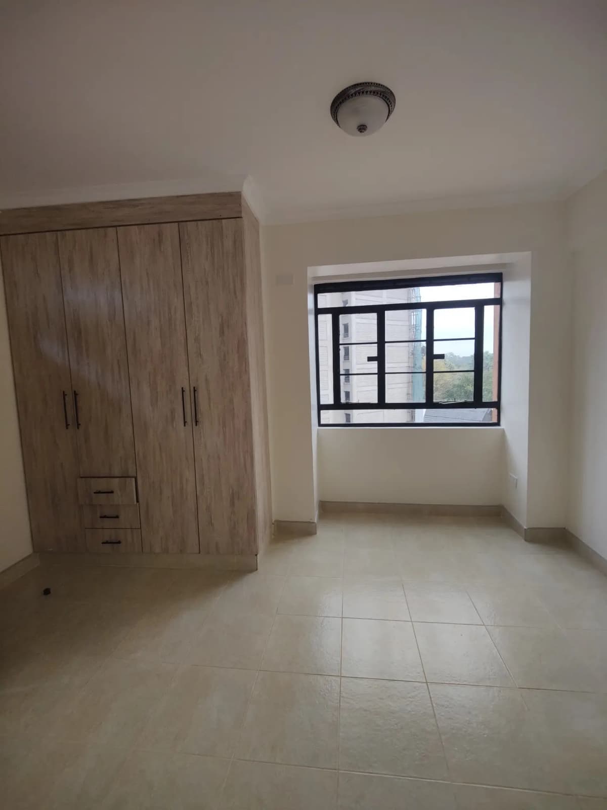 Spacious bedroom with built-in wooden wardrobe and bright window