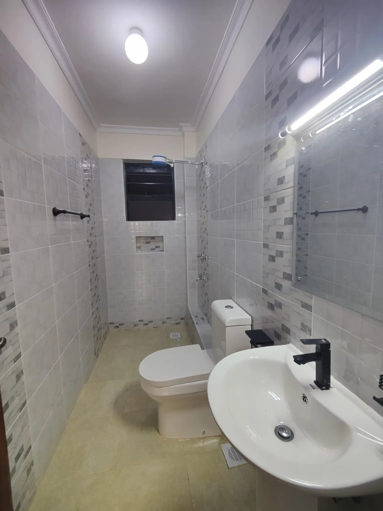 Modern bathroom with white tiles, sink, toilet, and shower area