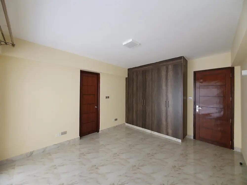 Spacious unfurnished bedroom with wooden wardrobes and doors