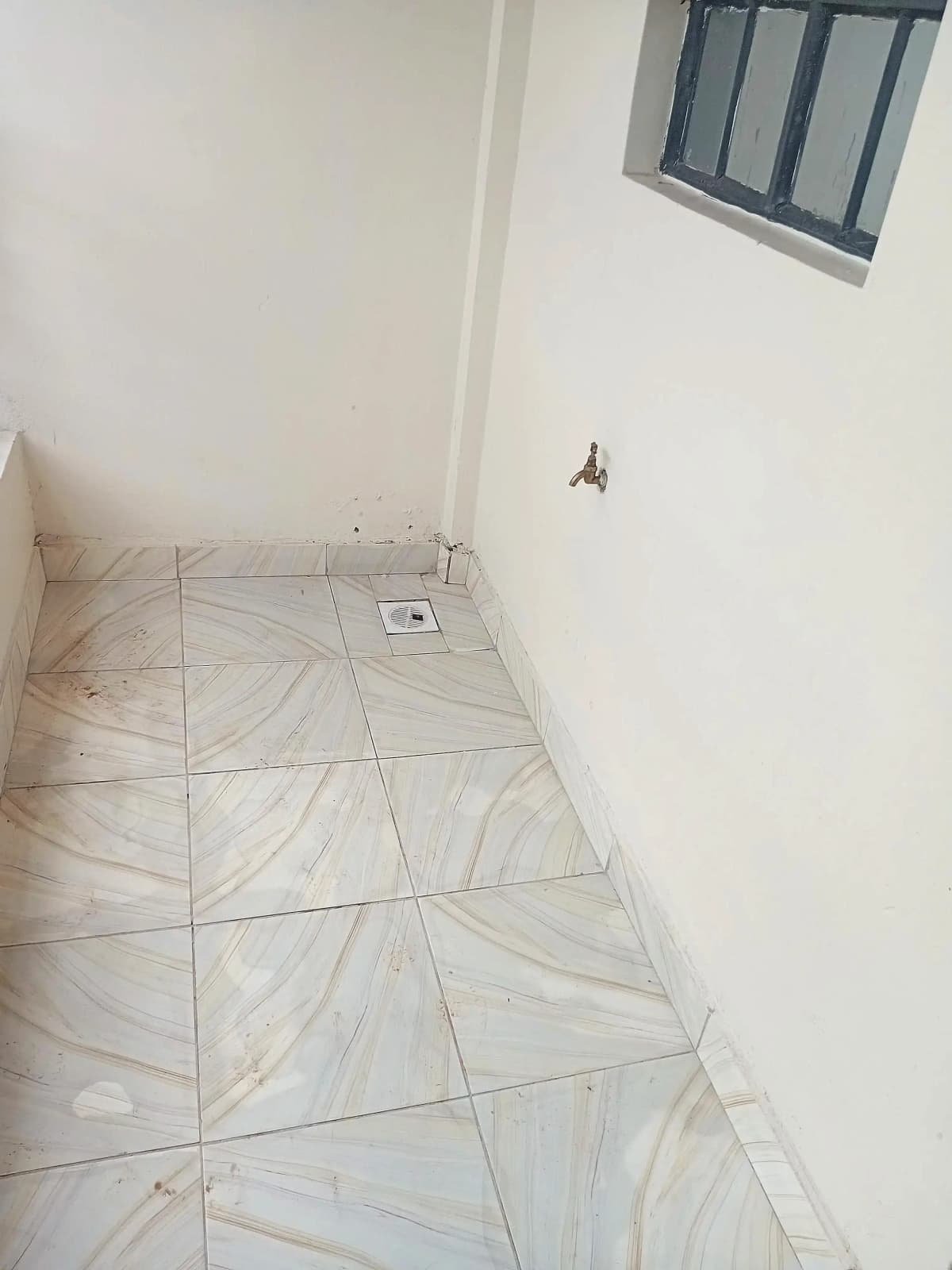 Tiled utility room with high window, minimal fixtures