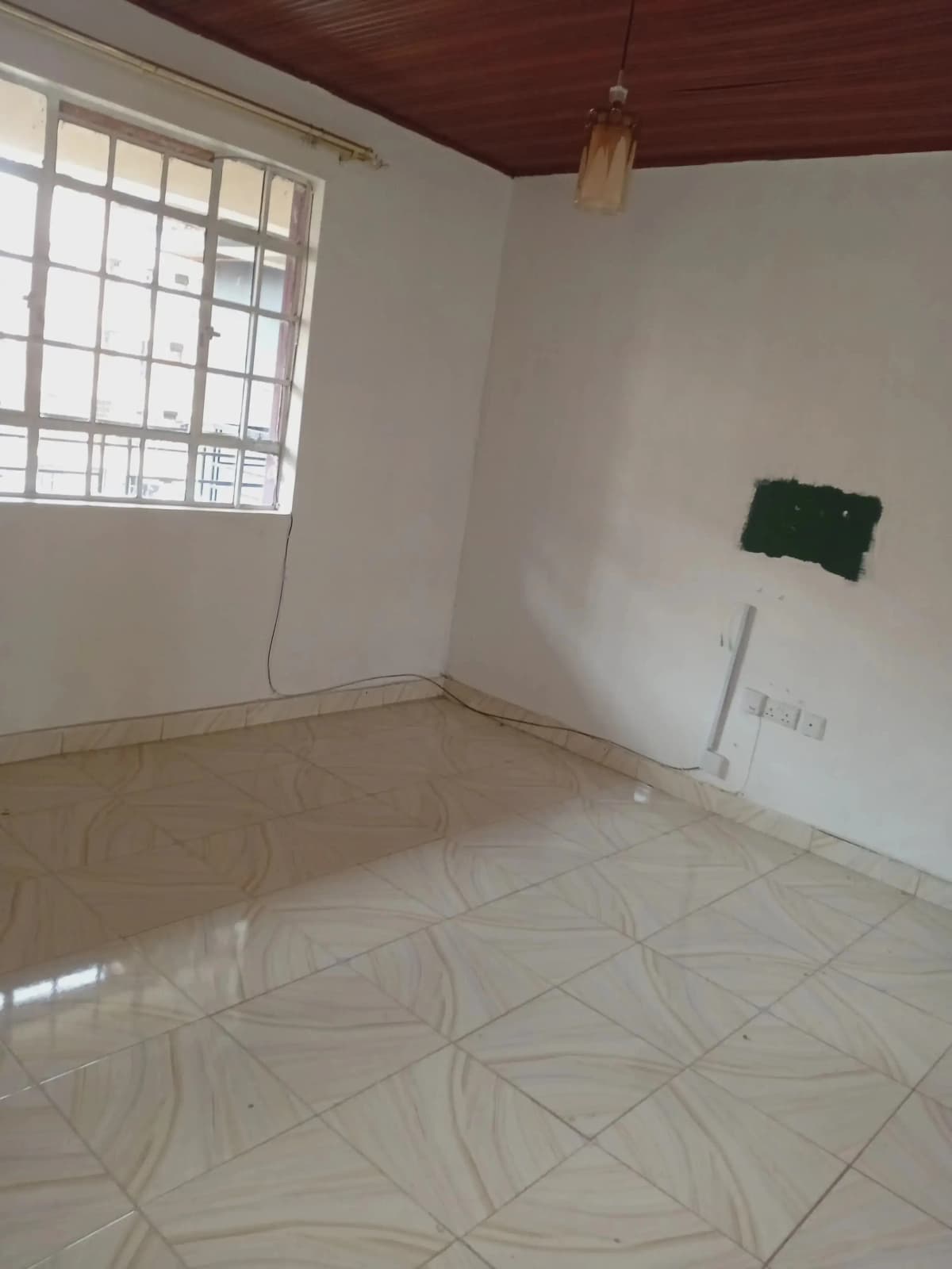 Empty bedroom with tiled floor and barred window