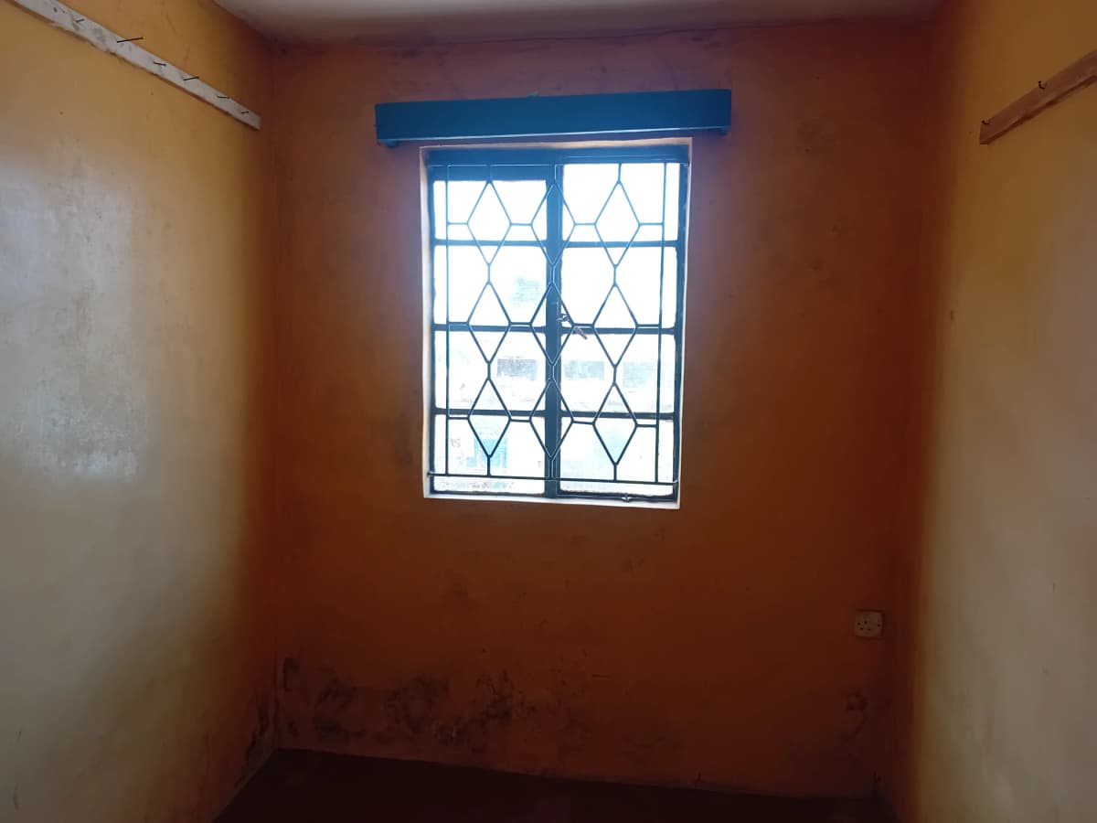 Compact bedroom with barred window, terracotta walls