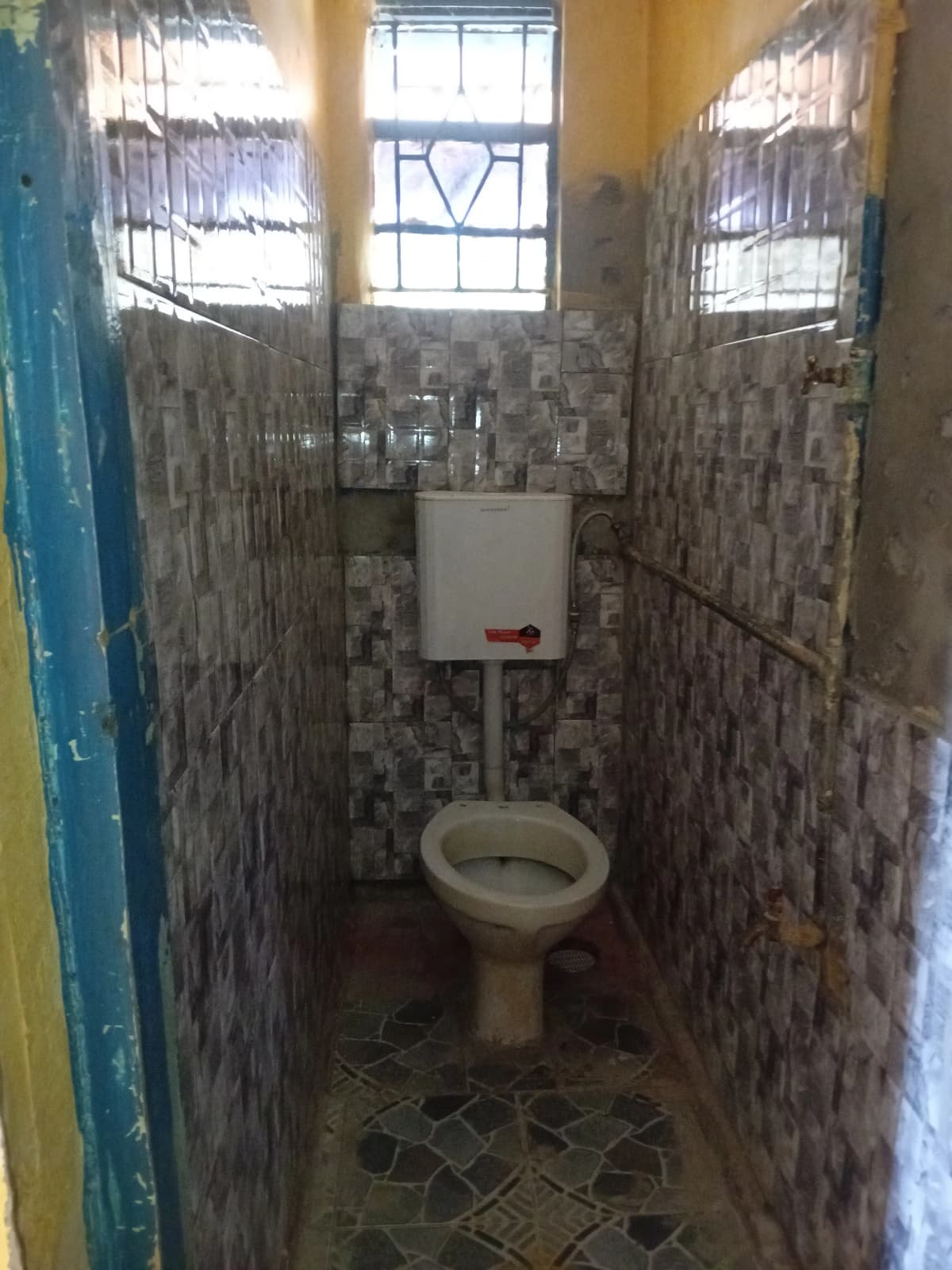 Basic toilet cubicle with tiled walls and small window