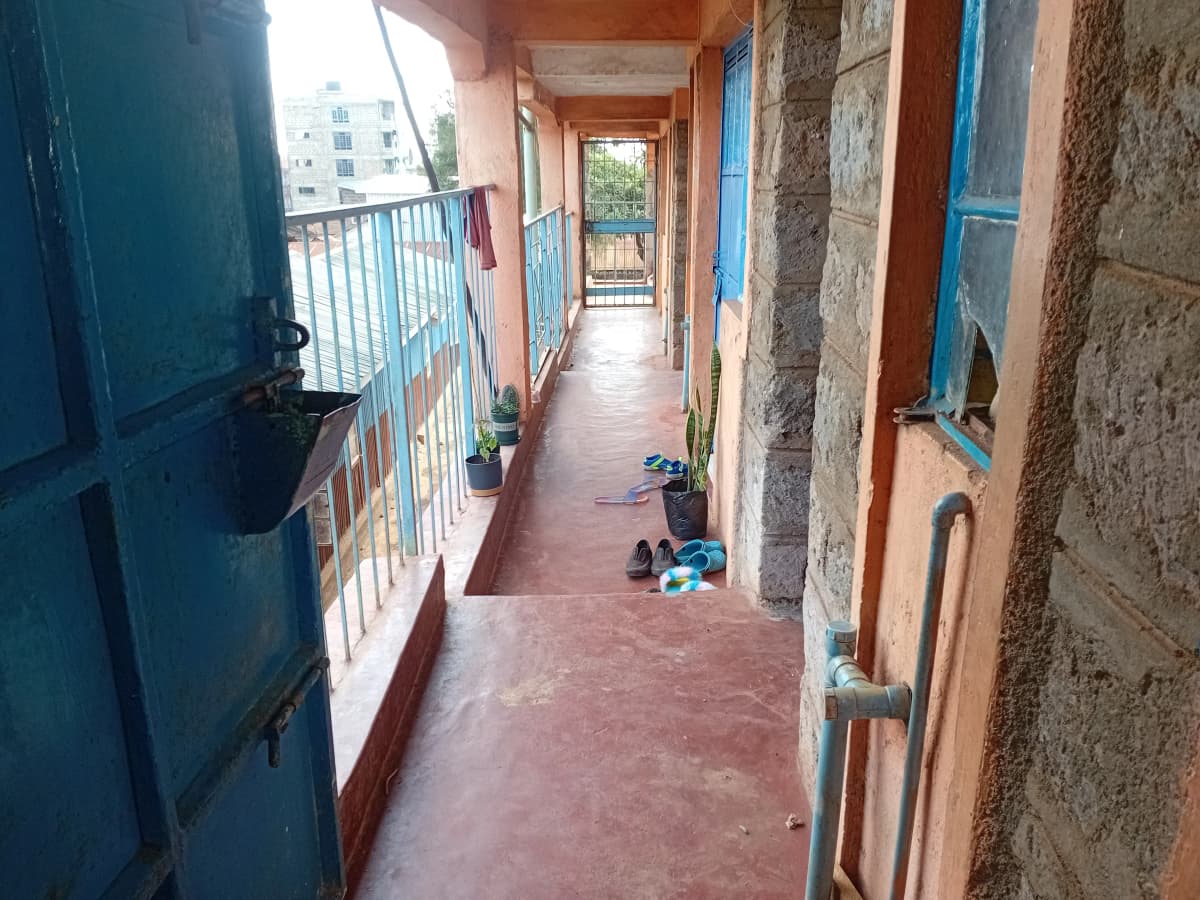 Long covered balcony with blue railings and terracotta flooring