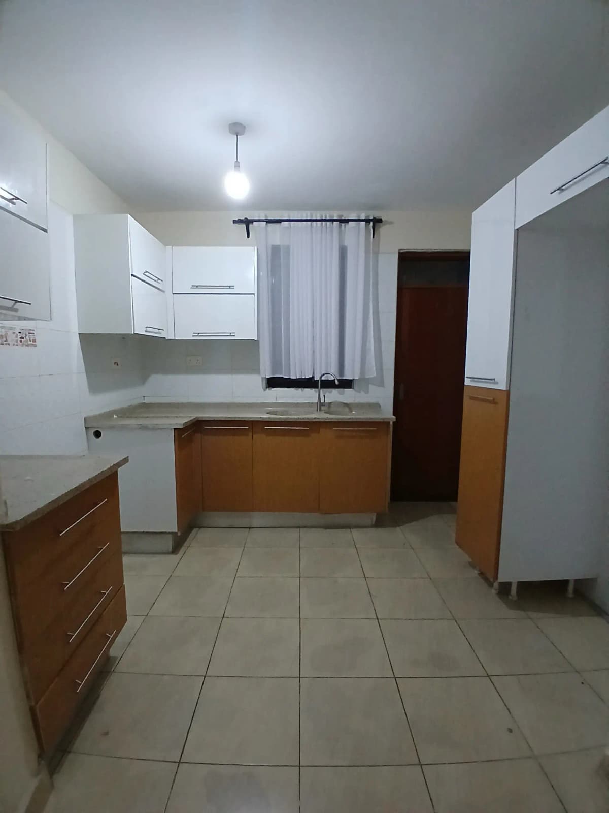Spacious kitchen with wooden cabinets and white upper units