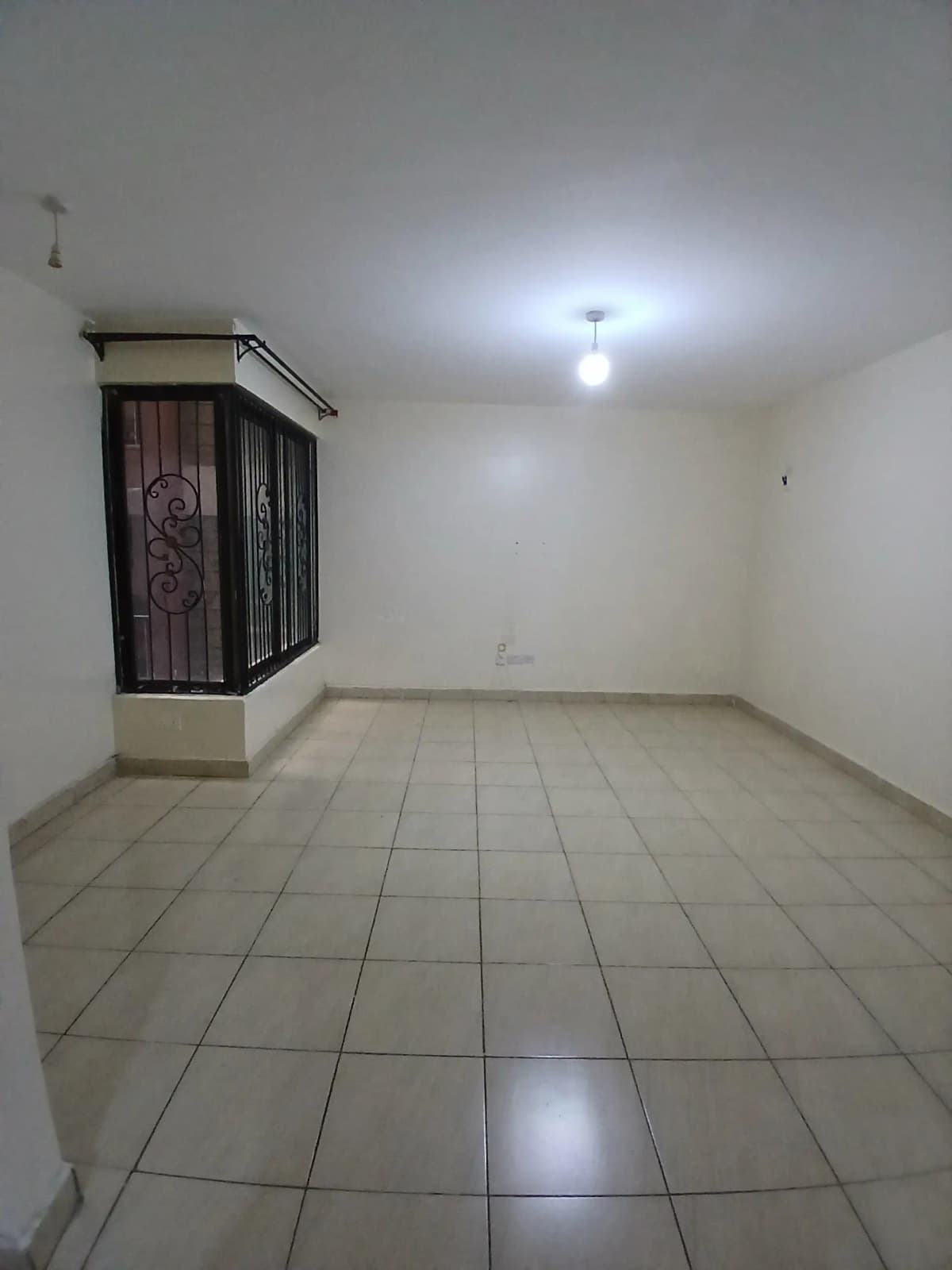 Empty living space with tile flooring and decorative window grille