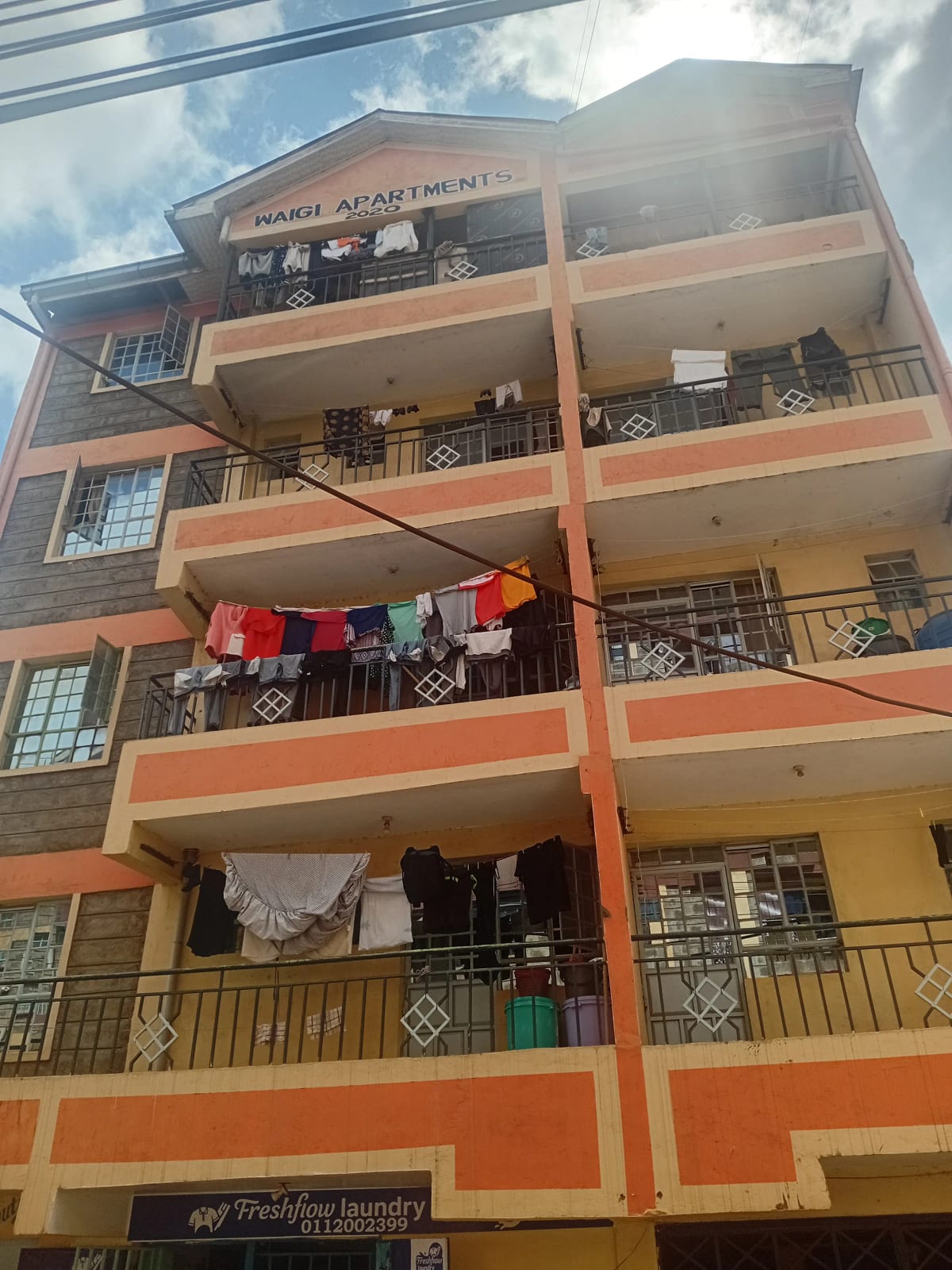 Multi-story residential building facade with orange and cream bands