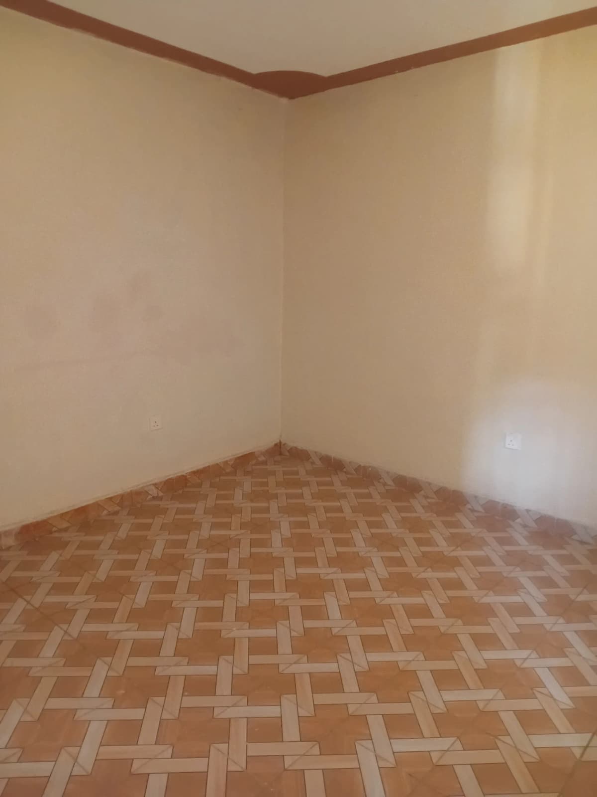 Empty bedroom with herringbone parquet flooring and beige walls