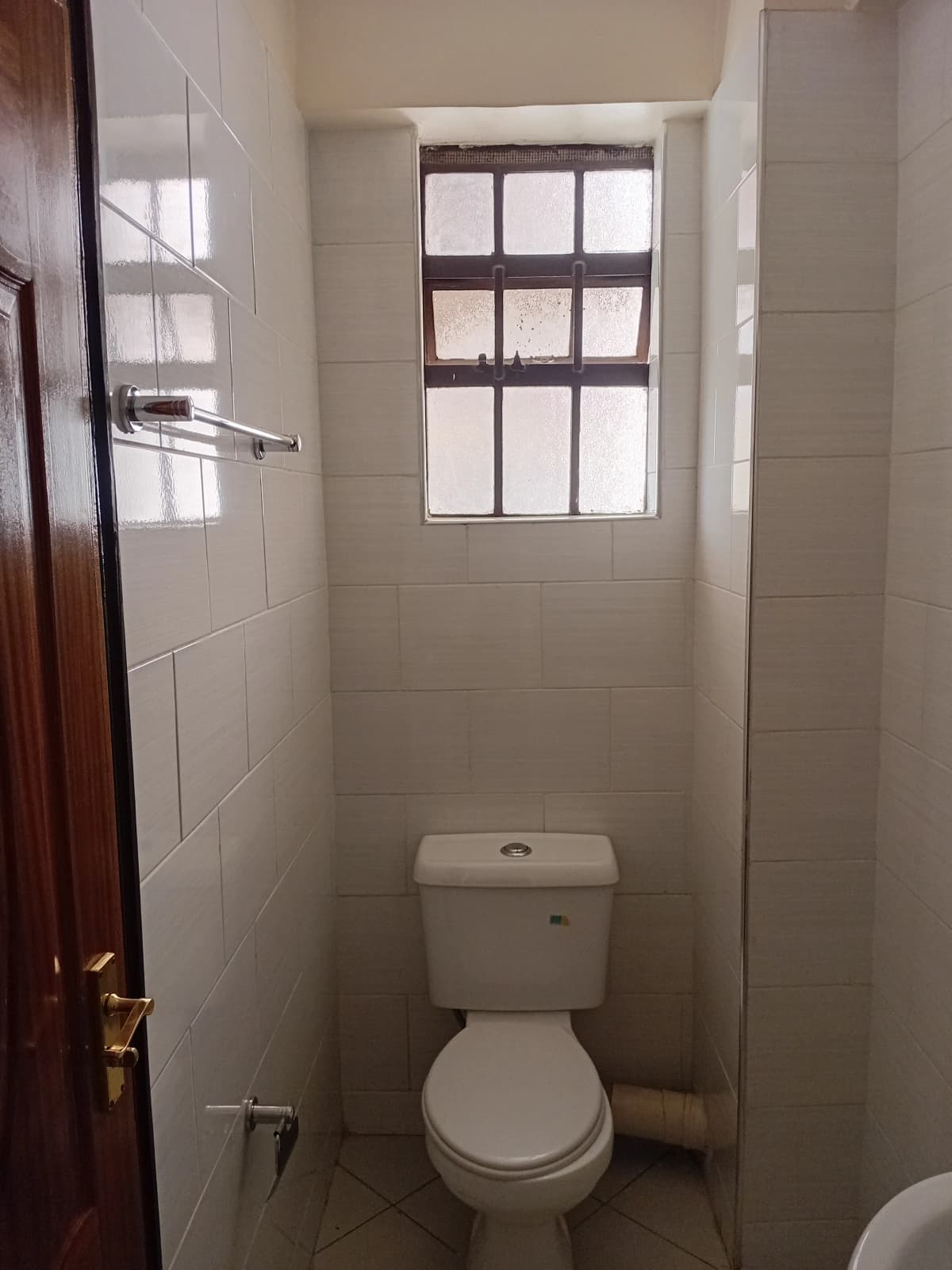 Compact toilet room with tiled walls and natural window light