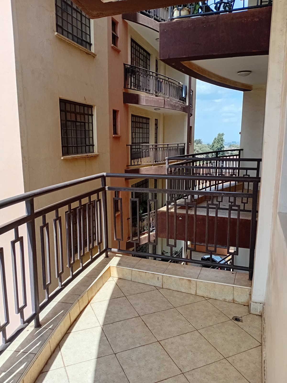 Spacious balcony with metal railings overlooking compound